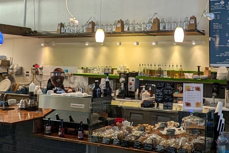 The bakery case at the coffee bar, filled with wrapped cookies, scones and bars with handwritten labels.