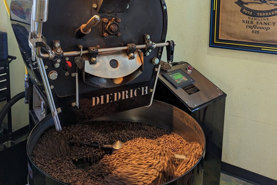 Fresh-roasted beans tumbling in the cooling tray of the Diedrich roaster in the shop.